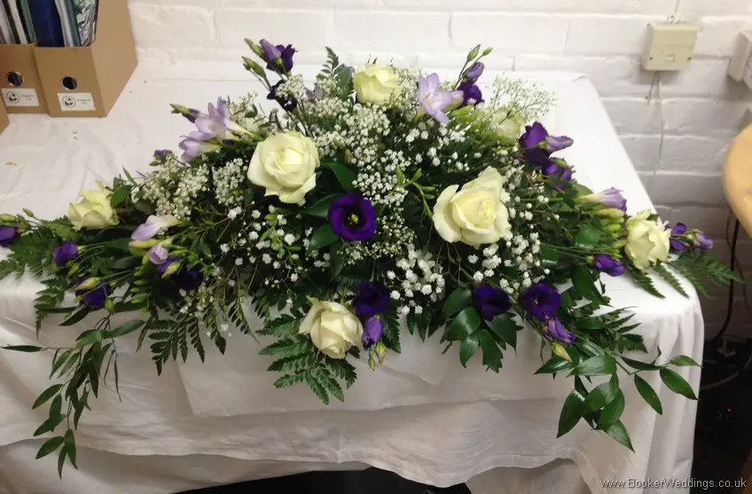 Purple and cream Top Table Long and Low Arrangement with ivory avalanche roses, purple lissianthus, lilac freesia and gypsophila