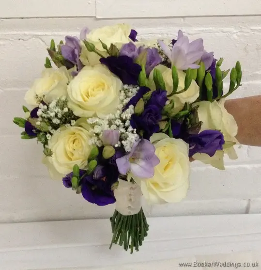 Purple and cream wedding flower Bridal Bouquet with ivory avalanche roses, purple lissianthus, lilac freesia and gypsophila Tilted View