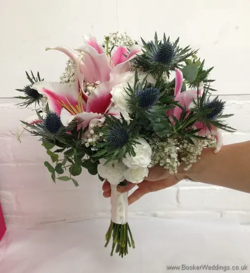 Bridal hand tied bouquet of Pink Stargazer lillies, white spray carnations, blue eryngium thistles, Gypsy Grass and Eucalyptus side view