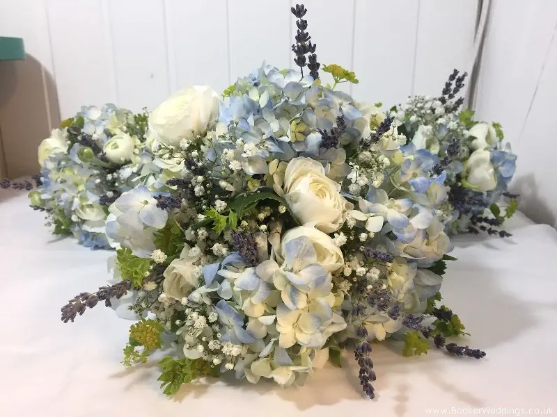 Bride and bridesmaid hand-tied bouquets in blue hydrangea, white ranunculus, burperlum, dried lavender and gypsy grass