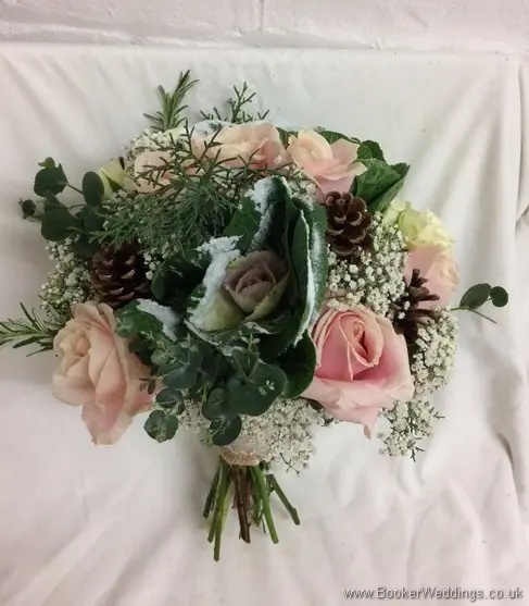 Winter wonderland bridal bouquet of blush roses ivory brassica, glitterd gypsy grass, conifer and pinecones_tilted view