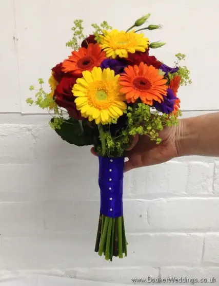 Bright and vibrant bridal hand-tied bouquet featuring roses, gerberas, lissianthus and alchamelia molis side view