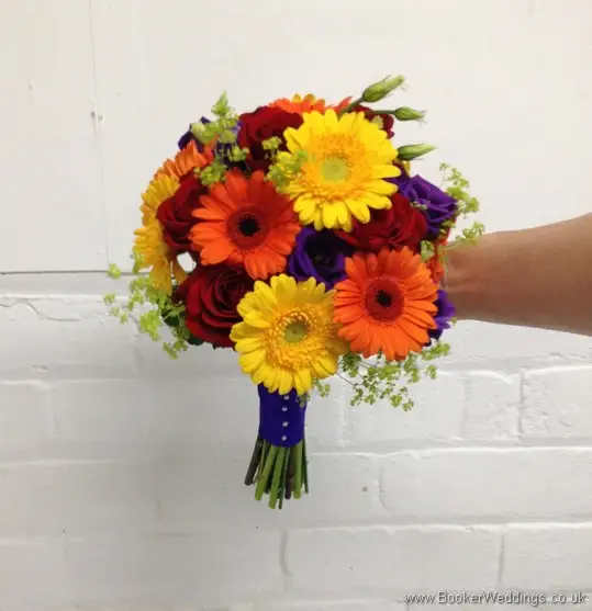 Bright and vibrant bridal hand-tied bouquet featuring roses, gerberas, lissianthus and alchamelia molis tilted view