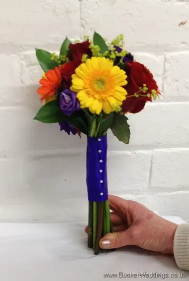 Bright and vibrant hand-tied bridesmaid bouquet featuring roses, gerberas, lissianthus and alchamelia molis side view