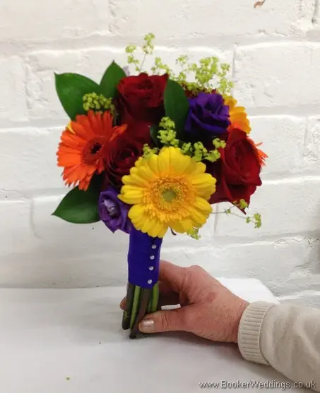 Bright and vibrant hand-tied bridesmaid bouquet featuring roses, gerberas, lissianthus and alchamelia molis tilted view