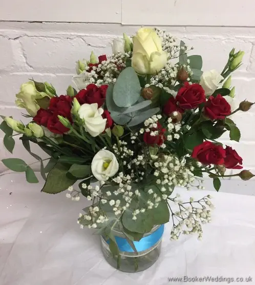 Top table arrangment of white and red flowers, including roses, spray roses, lissianthus and gypsophila