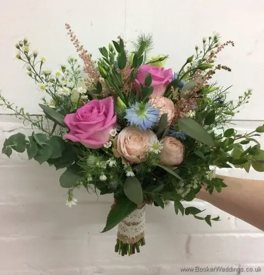 Rustic bridal bouquet in pink, cream and blue with roses, aster daisy, nigella, spray roses, astible, lissianthus and eucalyptus side view