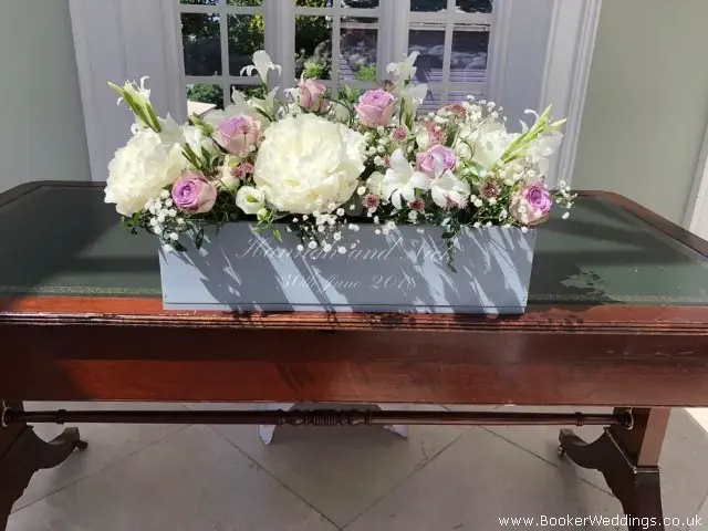 Registrar Table Arrangement in Personalised Crate Filled with Lilac and White Flowers