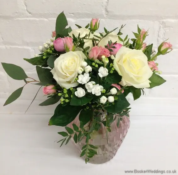Semi-wild pale pink and cream wedding reception table flower decorations in vases with roses, ranunculus, bouvardia, spray roses and eucalyptus