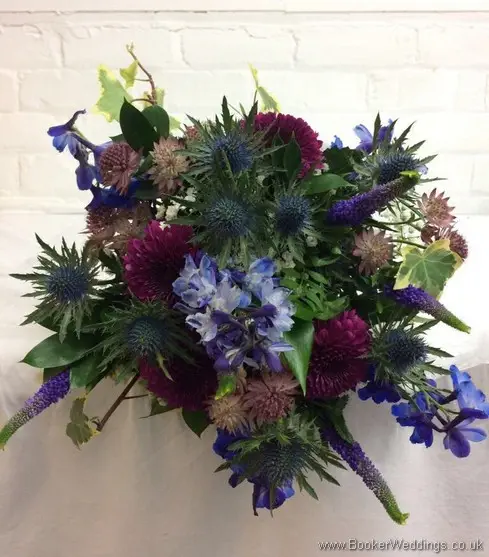 Blue & purple wild, rustic, country style bridal bouquet with delphinium, crysanthemum blooms, eryngium, astrantia, veronica, gypsophila and ivy top view
