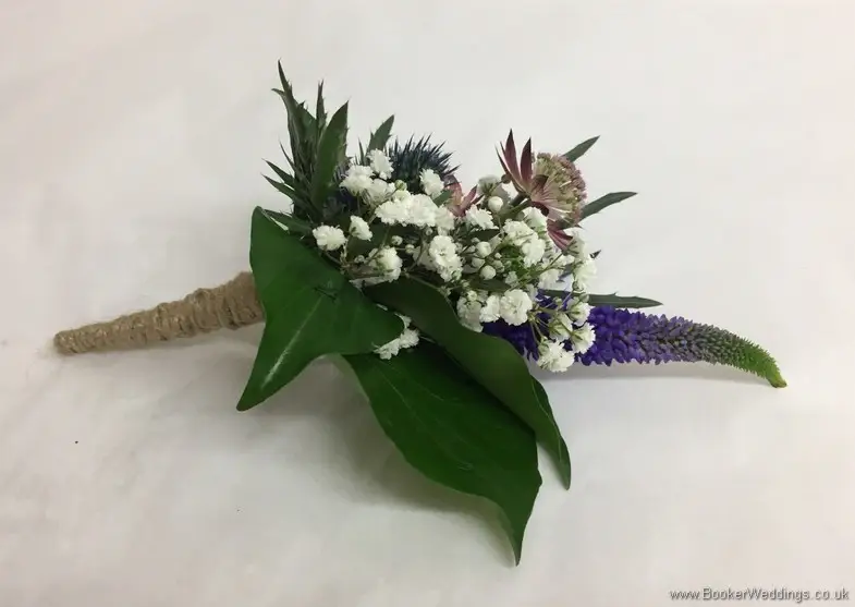 Rustic wild just picked blue and purple grooms buttonhole with eryngium, astrantia, veronica and gypsophila tied with twine side view