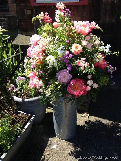 Large Milk Churn Arrangement for Entrance to Church with Peonies, aster, snapdragons, delphiniums, spray roses, stocks, tanacetum outside St Barnabus Church