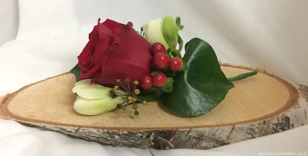 Christmas wedding groom buttonhole of red roses freesia and hypericum berries