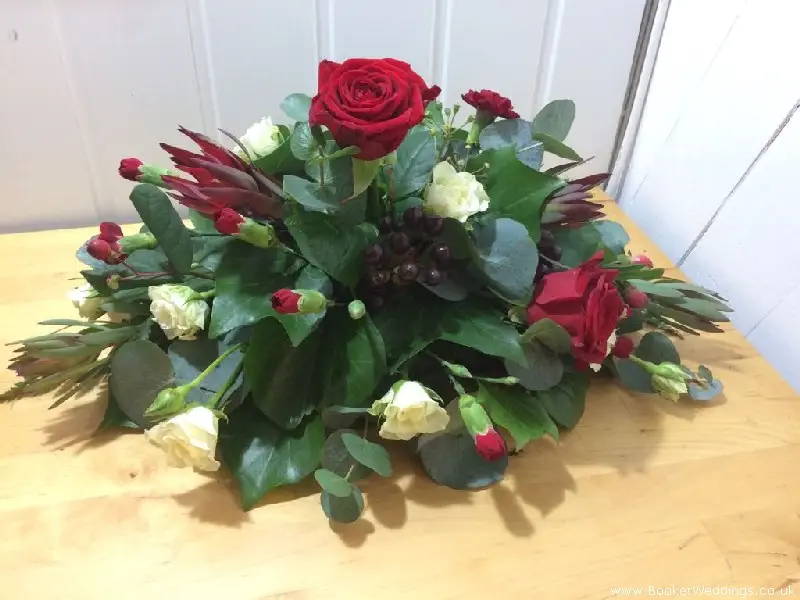 red rose centrepiece arrangement with white spray roses red spray carnations hypericum berries eucadendron and foliages