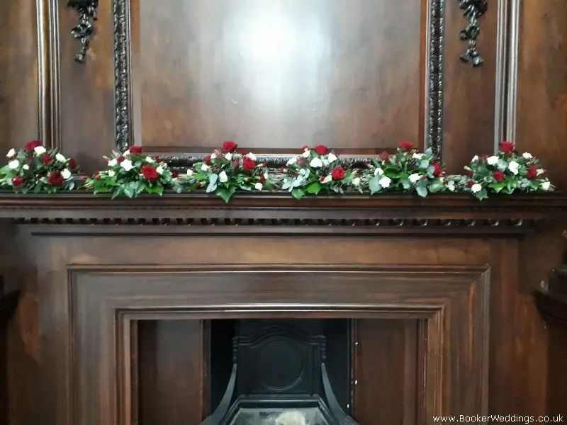wedding fireplace arrangement with red roses white spray roses red spray carnations hypericum berries eucadendron and foliages
