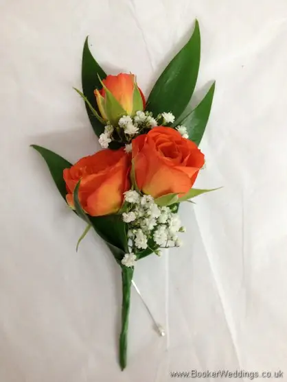 Bridal party buttonholes of orange spray roses and gypsophila