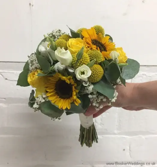 Bridesmaid handtied bouquet in yellow and creams with yellow sunflowers, craspedia, roses, gypsy grass, lissanthus and grey eucalyptus tilted view