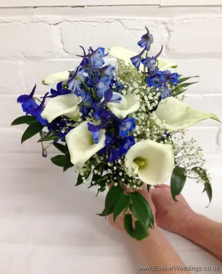 Bridesmaid hand-tied bouquet featuring White calla lillies, blue delphinium and gypsy grass tilted view