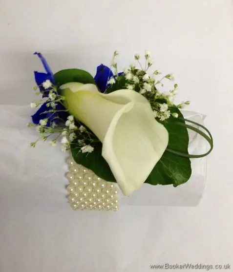 White calla lily, blue delphinium and gypsy grass wrist corsage on a pearl bracelet