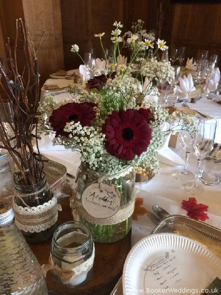wedding table centrepiece jam jars of gerbera gypsy grass and daisys