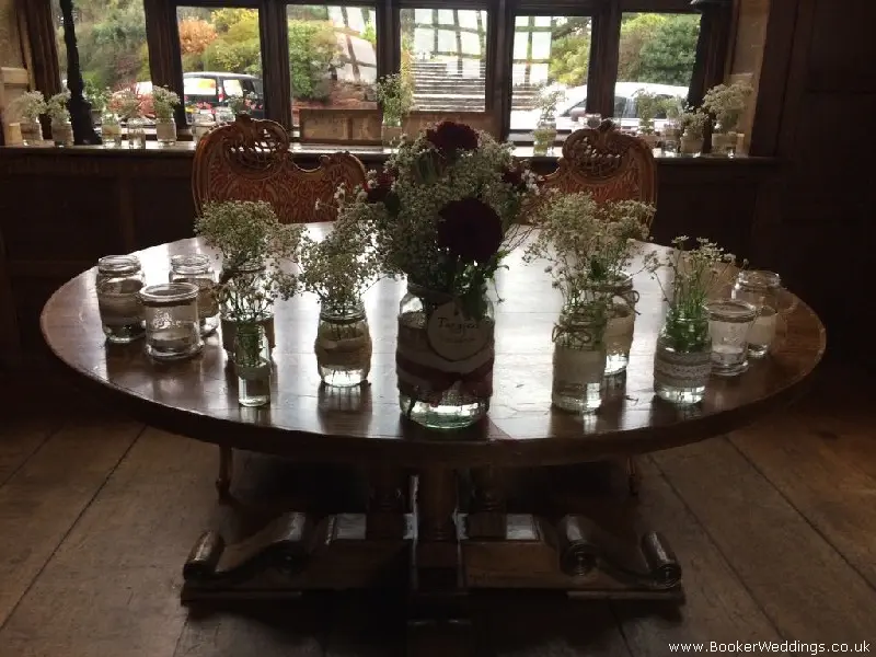 wedding table centrepieces jam jars of fresh flowers including gerbera gypsy grass and daisys